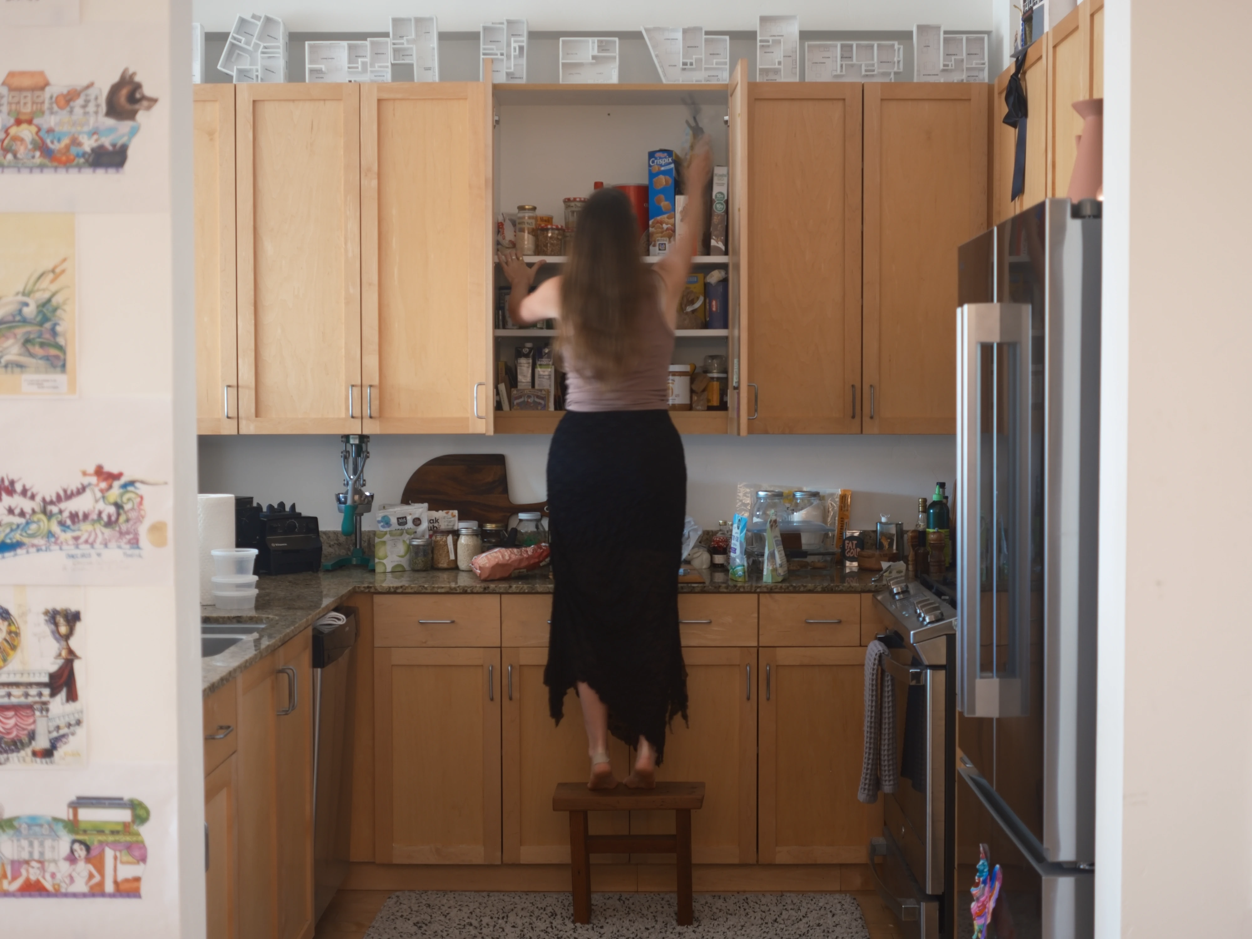 Gabrielle using the stool to reach a high cabinet